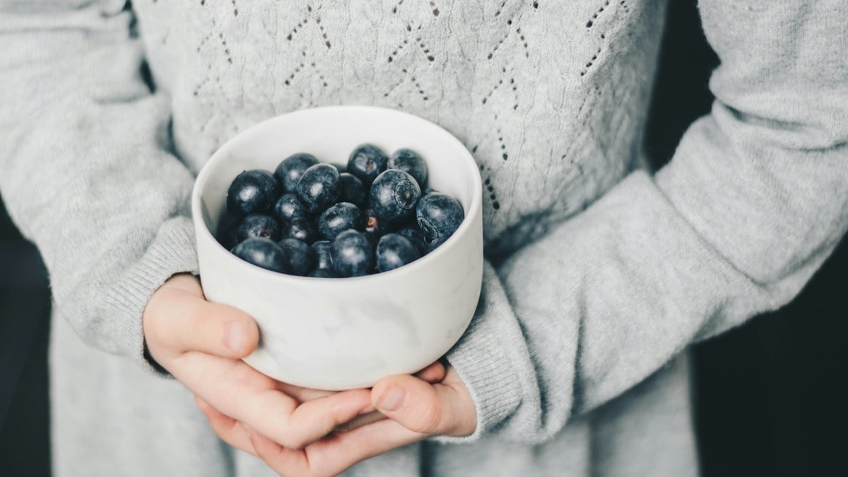 Little girl holding a bowl of blueberries